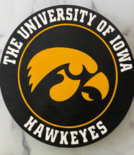 Load image into Gallery viewer, A round black wooden sign featuring the Hawkeyes