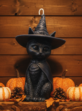 Load image into Gallery viewer, Celebrate the magic of Halloween with this enchanting Black Cat Beeswax Candle, handcrafted from 100% pure American beeswax. Featuring a charming black cat wearing a classic witch's hat adorned with a mystical triple moon symbol and skull centerpiece, this candle is the perfect accent for Halloween displays, gothic home décor, altars, and witchy spaces.