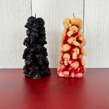 Load image into Gallery viewer, Unleash the spooky vibe with our one-of-a-kind bleeding skull beeswax candle. As it burns, watch in awe as the 'blood' oozes and the skulls roll off onto the plate, adding an eerie touch to your Halloween decorations. The glowing eyes and piles of skulls and bones make this pillar candle a must-have for gothic and fall decor. Perfect for gifting to skull-loving friends or for adding a touch of horror to any room. Get yours now and bring the creepy factor to your home!