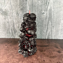 Load image into Gallery viewer, Unleash the spooky vibe with our one-of-a-kind bleeding skull beeswax candle. As it burns, watch in awe as the 'blood' oozes and the skulls roll off onto the plate, adding an eerie touch to your Halloween decorations. The glowing eyes and piles of skulls and bones make this pillar candle a must-have for gothic and fall decor. Perfect for gifting to skull-loving friends or for adding a touch of horror to any room. Get yours now and bring the creepy factor to your home!