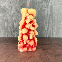 Load image into Gallery viewer, Unleash the spooky vibe with our one-of-a-kind bleeding skull beeswax candle. As it burns, watch in awe as the 'blood' oozes and the skulls roll off onto the plate, adding an eerie touch to your Halloween decorations. The glowing eyes and piles of skulls and bones make this pillar candle a must-have for gothic and fall decor. Perfect for gifting to skull-loving friends or for adding a touch of horror to any room. Get yours now and bring the creepy factor to your home!
