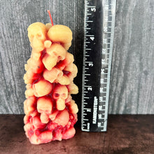 Load image into Gallery viewer, Unleash the spooky vibe with our one-of-a-kind bleeding skull beeswax candle. As it burns, watch in awe as the 'blood' oozes and the skulls roll off onto the plate, adding an eerie touch to your Halloween decorations. The glowing eyes and piles of skulls and bones make this pillar candle a must-have for gothic and fall decor. Perfect for gifting to skull-loving friends or for adding a touch of horror to any room. Get yours now and bring the creepy factor to your home!