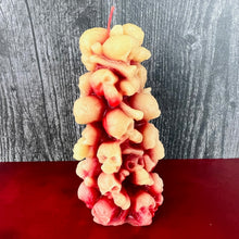 Load image into Gallery viewer, Unleash the spooky vibe with our one-of-a-kind bleeding skull beeswax candle. As it burns, watch in awe as the 'blood' oozes and the skulls roll off onto the plate, adding an eerie touch to your Halloween decorations. The glowing eyes and piles of skulls and bones make this pillar candle a must-have for gothic and fall decor. Perfect for gifting to skull-loving friends or for adding a touch of horror to any room. Get yours now and bring the creepy factor to your home!