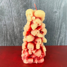 Load image into Gallery viewer, Unleash the spooky vibe with our one-of-a-kind bleeding skull beeswax candle. As it burns, watch in awe as the 'blood' oozes and the skulls roll off onto the plate, adding an eerie touch to your Halloween decorations. The glowing eyes and piles of skulls and bones make this pillar candle a must-have for gothic and fall decor. Perfect for gifting to skull-loving friends or for adding a touch of horror to any room. Get yours now and bring the creepy factor to your home!