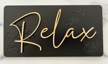 Load image into Gallery viewer, Transform your bathroom into a serene oasis with these Beautiful Relax, Soak, Unwind signs. Crafted from high-quality wood, each sign features delicate embossing of subtle flowers and foliage, creating a soft, nature-inspired background. Perfectly sized at 11 1/2” long x 6” tall, these signs effortlessly add a calming spa-like touch to any space. Whether you're creating a tranquil retreat or enhancing your bathroom's décor, these elegant signs bring a sense of peace and relaxation to your home.