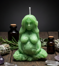 Load image into Gallery viewer, Honor the beauty, balance, and abundance of nature with this handcrafted Gaia Mother Earth Beeswax Candle. Symbolizing the nurturing spirit of Mother Earth, this stunning candle depicts Gaia gently holding the Earth in her hands beneath the sun, moon, and stars. Flowing vines and leaves intertwine throughout her body, while the infinity symbol on her third eye represents wisdom, spiritual connection, and the endless cycle of life.