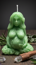 Load image into Gallery viewer, Honor the beauty, balance, and abundance of nature with this handcrafted Gaia Mother Earth Beeswax Candle. Symbolizing the nurturing spirit of Mother Earth, this stunning candle depicts Gaia gently holding the Earth in her hands beneath the sun, moon, and stars. Flowing vines and leaves intertwine throughout her body, while the infinity symbol on her third eye represents wisdom, spiritual connection, and the endless cycle of life.