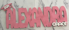 Load image into Gallery viewer, Celebrate your graduate with this personalized wooden graduation sign. An ideal alternative to a traditional guestbook, it features their name (or last name) and graduation year, making it a great photo prop for the special day. Show your support in style with this meaningful keepsake.