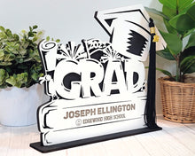 Load image into Gallery viewer, This Graduation Tassel Holder is the perfect way to commemorate your special event. It is designed to securely hold your tassel in place and is personalized with your name, graduation year or a personalized message. Show off your style and pride with a custom made holder that you can use to display your graduation tassel.  Available in 2023, 2024, 2025 and 2026 styles.