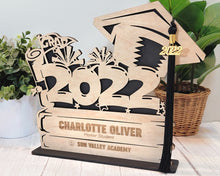 Load image into Gallery viewer, This Graduation Tassel Holder is the perfect way to commemorate your special event. It is designed to securely hold your tassel in place and is personalized with your name, graduation year or a personalized message. Show off your style and pride with a custom made holder that you can use to display your graduation tassel.  Available in 2023, 2024, 2025 and 2026 styles.