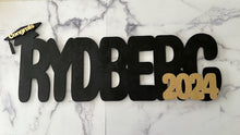 Load image into Gallery viewer, Celebrate your graduate with this personalized wooden graduation sign. An ideal alternative to a traditional guestbook, it features their name (or last name) and graduation year, making it a great photo prop for the special day. Show your support in style with this meaningful keepsake.