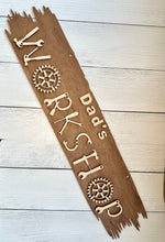 Load image into Gallery viewer, welcome one and all to your creative haven and personalize this sign with your favorite craftsman's name prominently displayed at the top. Crafted with care, this sign is more than just an entrance statement; it's a celebration of your passion for creating. The workshop letters are uniquely formed from an array of tools, adding a whimsical touch that speaks directly to the heart of every craftsman.