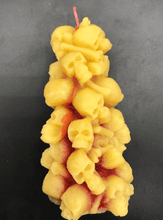 Load image into Gallery viewer, Bleeding Skull Beeswax Candle, piles of skulls and bones with a red leaking core.