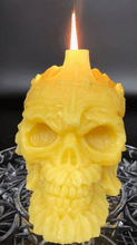 Load image into Gallery viewer, Creepy, ornate skull beeswax candle with cross crown.  Eyes glow after it starts to burn down.