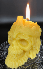 Load image into Gallery viewer, Creepy, ornate skull beeswax candle with cross crown.  Eyes glow after it starts to burn down.