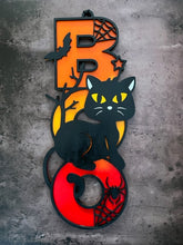Load image into Gallery viewer, Light up your Halloween decor with this incredible Cat Boo sign.  The perfect addition to your spooky Halloween decor! This adorable black cat design is sure to charm your guest and add a playful touch to your home.  Featuring a whimsical black cat with bats and spider webs, this decorative piece sits atop the word "BOO" in bright orange, yellow and red, making it a vibrant and eye-catching accent for any space.