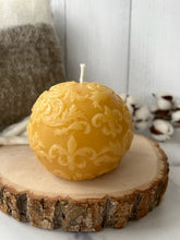 Load image into Gallery viewer, This beautiful sphere Fleur De Lis beeswax candle is a great addition to a dining room table or an entryway and can make a fantastic gift for anyone who loves the New Orleans Saints or is of French ancestry. The soft light of the beeswax illuminates the Fleur De Lis design beautifully as it lights up your room. Available in natural, purple or green.