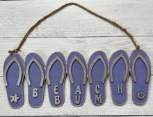 Load image into Gallery viewer, Add a bit of summer to your entry way with this Flip Flop Welcome Door Hanger Sign.  These adorable flip flops spelling out WELCOME invite guest into your home.  Perfect for lake houses, beach retreats or just to add a bit of summer decor.  Also available in Beach Bum design.  A line of seven flip flops with the words Welcome or Beach Bum across the bottom.
