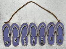 Load image into Gallery viewer, Add a bit of summer to your entry way with this Flip Flop Welcome Door Hanger Sign.  These adorable flip flops spelling out WELCOME invite guest into your home.  Perfect for lake houses, beach retreats or just to add a bit of summer decor.  Also available in Beach Bum design.  A line of seven flip flops with the words Welcome or Beach Bum across the bottom.