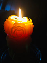 Load image into Gallery viewer, Beautiful glow of roses that are carved into the sides of the rose beeswax candle when it's lit.