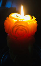 Load image into Gallery viewer, Beautiful glow of roses that are carved into the sides of the rose beeswax candle when it's lit.