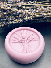 Load image into Gallery viewer, Purple round bar of lotion with lavender bouquet design in the middle. 3.5 oz approx. weight. These handy lotion bars are great when you're on the go or for everyday use! Natural body heat slightly melts a bit of the lotion onto your hands. Great for elbows and dry areas. It leaves your skin feeling smooth and hydrated. The beeswax adds a barrier of protection that keeps the lotion where you put it longer. Made by hand in the USA.