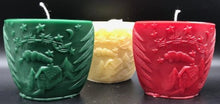 Load image into Gallery viewer, Oval all natural beeswax candle with Santa and his reindeer flying over a house in the woods. Pine tree design adorns the edges of the candle. Handmade in the USA.