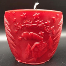 Load image into Gallery viewer, Oval all natural beeswax candle with Santa and his reindeer flying over a house in the woods. Pine tree design adorns the edges of the candle. Handmade in the USA.