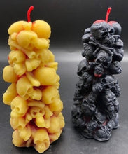 Load image into Gallery viewer, Bleeding Skull Beeswax Candle, piles of skulls and bones with a red leaking core.