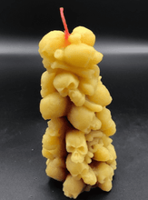 Load image into Gallery viewer, Bleeding Skull Beeswax Candle, piles of skulls and bones with a red leaking core.