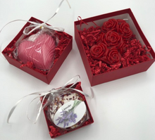 Load image into Gallery viewer, That special someone is sure to feel the love this Valentines Day when they open this fantastic Valentines Day Gift Box Trio.  A stack of 3 red boxes tied with a white ribbon.  Set contains 1 Red Beeswax Rose Pillar Candle, 1 Lavender Bath Bomb &amp; 1 Heart Shaped Goat&#39;s Milk Soap in either Lavender or Rose Geranium scents.
