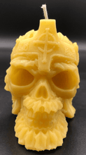 Load image into Gallery viewer, Creepy, ornate skull beeswax candle with cross crown.  Eyes glow after it starts to burn down.