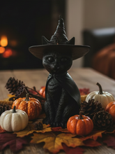Load image into Gallery viewer, Celebrate the magic of Halloween with this enchanting Black Cat Beeswax Candle, handcrafted from 100% pure American beeswax. Featuring a charming black cat wearing a classic witch's hat adorned with a mystical triple moon symbol and skull centerpiece, this candle is the perfect accent for Halloween displays, gothic home décor, altars, and witchy spaces.
