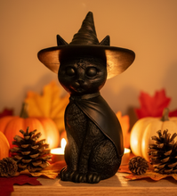 Load image into Gallery viewer, Celebrate the magic of Halloween with this enchanting Black Cat Beeswax Candle, handcrafted from 100% pure American beeswax. Featuring a charming black cat wearing a classic witch's hat adorned with a mystical triple moon symbol and skull centerpiece, this candle is the perfect accent for Halloween displays, gothic home décor, altars, and witchy spaces.
