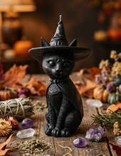 Load image into Gallery viewer, Celebrate the magic of Halloween with this enchanting Black Cat Beeswax Candle, handcrafted from 100% pure American beeswax. Featuring a charming black cat wearing a classic witch's hat adorned with a mystical triple moon symbol and skull centerpiece, this candle is the perfect accent for Halloween displays, gothic home décor, altars, and witchy spaces.
