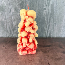 Load image into Gallery viewer, Unleash the spooky vibe with our one-of-a-kind bleeding skull beeswax candle. As it burns, watch in awe as the 'blood' oozes and the skulls roll off onto the plate, adding an eerie touch to your Halloween decorations. The glowing eyes and piles of skulls and bones make this pillar candle a must-have for gothic and fall decor. Perfect for gifting to skull-loving friends or for adding a touch of horror to any room. Get yours now and bring the creepy factor to your home!
