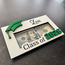 Load image into Gallery viewer, Looking for a unique and thoughtful way to give cash to your favorite graduate? Our Personalized Graduation Money Holder is handcrafted from quality wood and features a bold Cap &amp; 2025 design that can be customized in your choice of colors—perfect for matching school colors or your grad's favorites!
