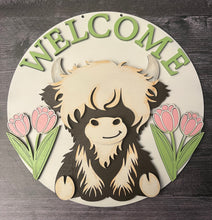 Load image into Gallery viewer, Welcome guests in the sweetest way with this adorable Highland Cow Door Hanger! Featuring a charming Highland cow design with WELCOME displayed across the top and cheerful tulips on each side, this piece is the perfect accent to brighten your entryway and celebrate the beauty of spring.

