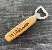 Load image into Gallery viewer, Pop open your favorite beverage in style with our engraved wood-handled bottle openers! Crafted with a durable stainless steel opener and a smooth wooden handle, these openers offer a comfortable grip and a sleek, rustic look.
