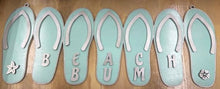 Load image into Gallery viewer, Add a bit of summer to your entry way with this Flip Flop Welcome Door Hanger Sign.  These adorable flip flops spelling out WELCOME invite guest into your home.  Perfect for lake houses, beach retreats or just to add a bit of summer decor.  
