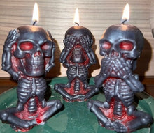 Load image into Gallery viewer, Each beeswax candle measures 4&quot; tall x 2 3/16&quot; wide, and weighs approximately 2 ounces, makin them the perfect size for any room in your home. The three skulls feature a unique design, embodying the classic &quot;see no evil, hear no evil, speak no evil&quot; phrase. Available in a black exterior with red core or a yellow exterior with red core.  Picture of all three candles burning.
