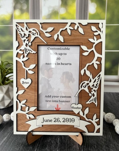 This Hummingbird Photo Frame is the perfect way to display your cherished memories with loved ones. This unique and personalized photo frame can be customized with up to 20 names in the hearts hung around the frame and custom wording in the banner across the bottom, making it a special and meaningful addition to any home decor. Available for a 4