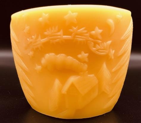 Oval all natural beeswax candle with Santa and his reindeer flying over a house in the woods. Pine tree design adorns the edges of the candle. Handmade in the USA.