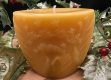 Load image into Gallery viewer, Oval all natural beeswax candle with Santa and his reindeer flying over a house in the woods. Pine tree design adorns the edges of the candle. Handmade in the USA.
