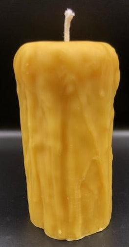 Rustic Beeswax Pillar candle with wax drip pattern flowing down the sides.