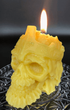 Load image into Gallery viewer, Creepy, ornate skull beeswax candle with cross crown.  Eyes glow after it starts to burn down.  Lit.
